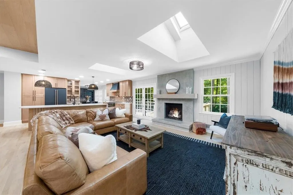Living room with a skylight, light wood-type flooring, a fireplace, and crown molding