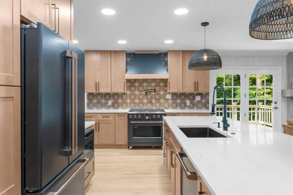 Kitchen with recessed lighting, high quality appliances, tasteful backsplash, decorative light fixtures, and light stone countertops