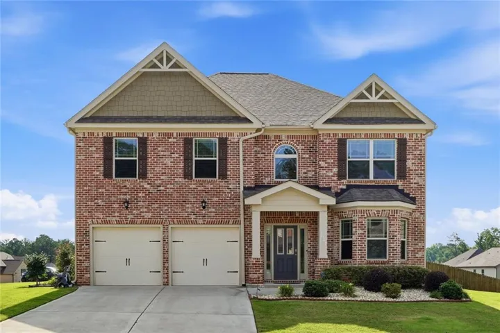 Brick facade residence featuring a two-car garage, covered entry porch, and decorative shutters