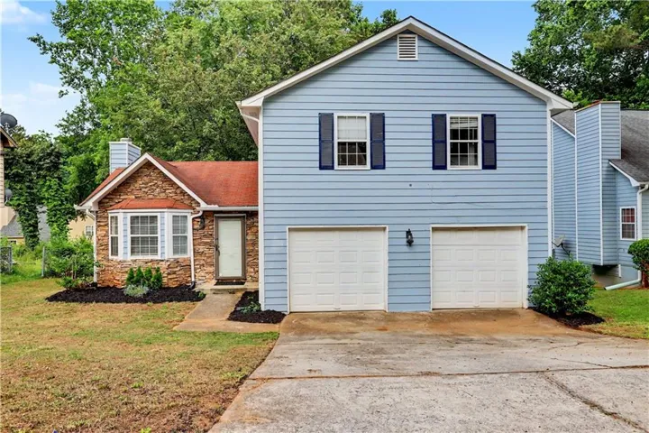 Exterior featuring light blue horizontal siding, stone facade, a two-car garage, and dark blue window shutters