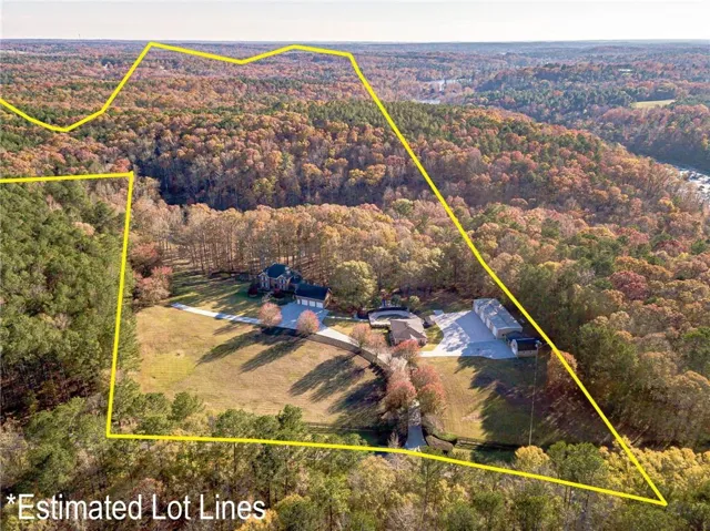 Expansive property featuring a large residence, separate detached garage structures, and extensive forested areas