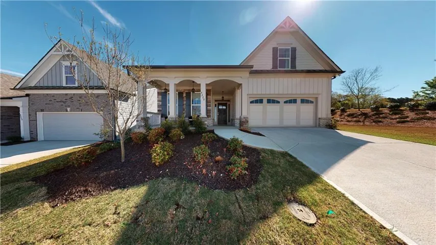 Columned front porch, two-car garage, brick and board-and-batten siding, landscaped front yard, and a paved driveway