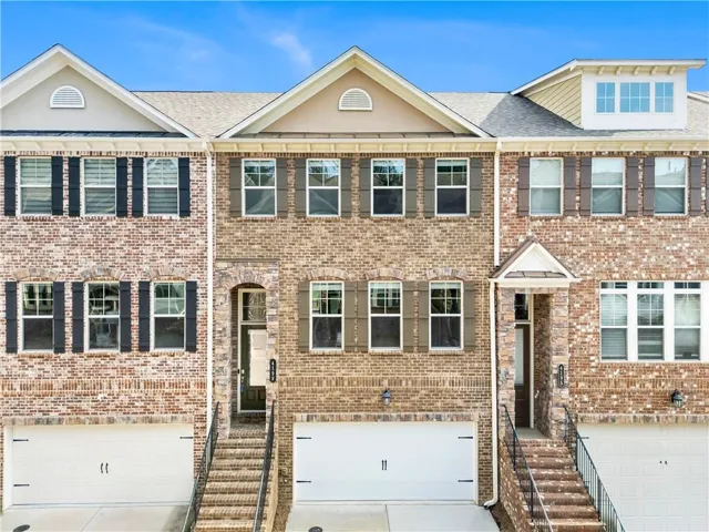 Brick exterior with multiple windows, arched entry, decorative gables, and individual garages