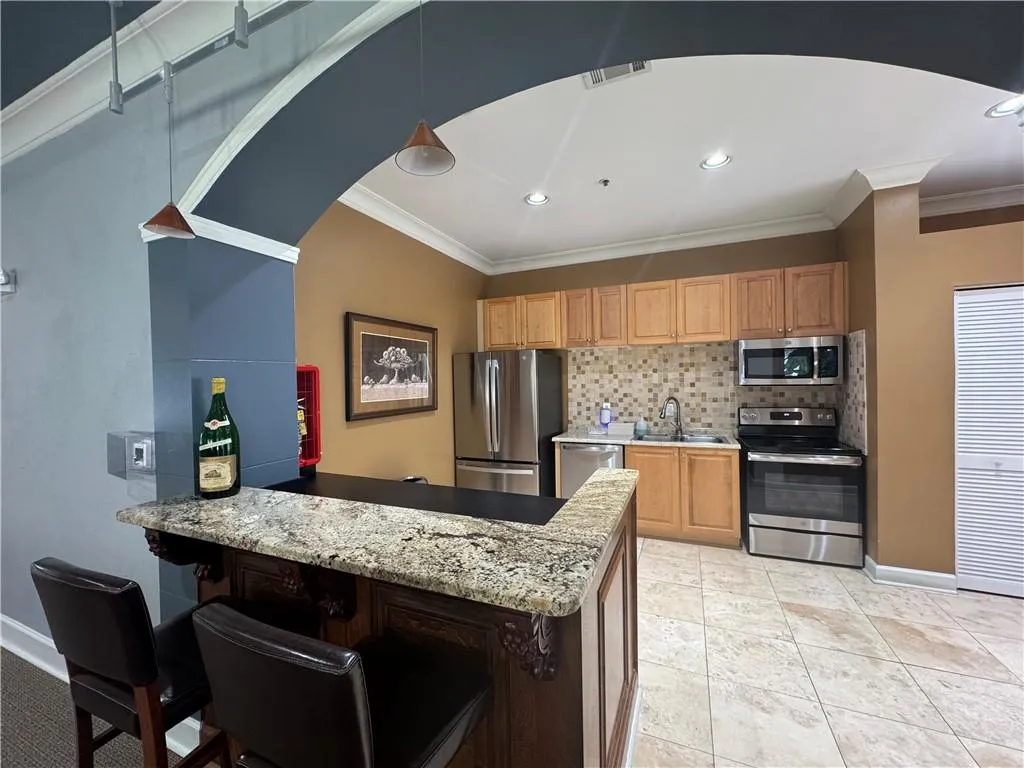 Kitchen with stainless steel appliances, tasteful backsplash, recessed lighting, a peninsula, and decorative light fixtures