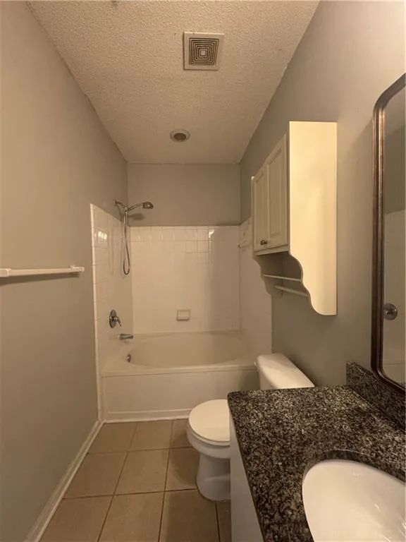 Bathroom featuring a textured ceiling, tile patterned floors, vanity, and shower / bathtub combination