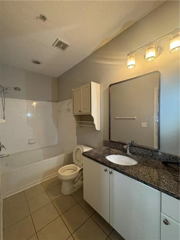 Full bath with a textured ceiling, vanity, tile patterned flooring, and shower / bath combination