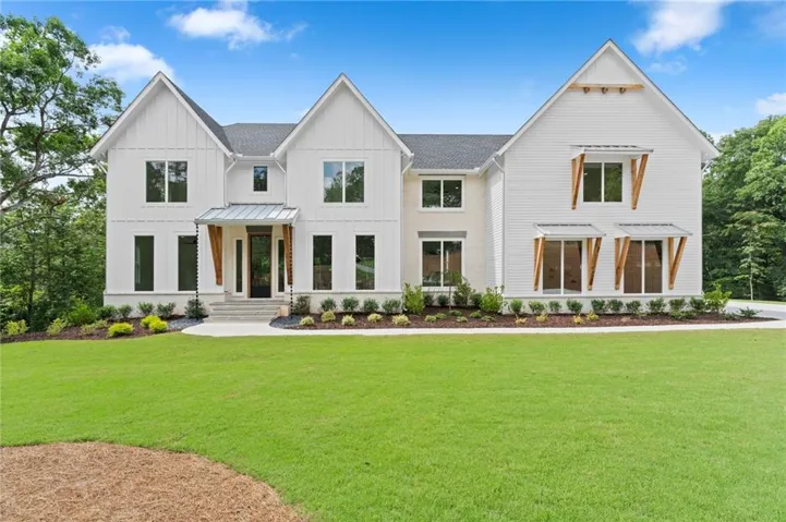 Contemporary two-story exterior featuring white board and batten siding, multiple gables, a dark shingle roof, and an inviting front entry with a metal awning