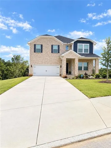 Brick facade with black shutters, two-car garage, and a concrete driveway