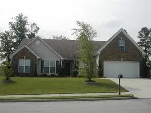 Brick and siding exterior with a pitched roof, attached two-car garage, manicured lawn, and paved driveway