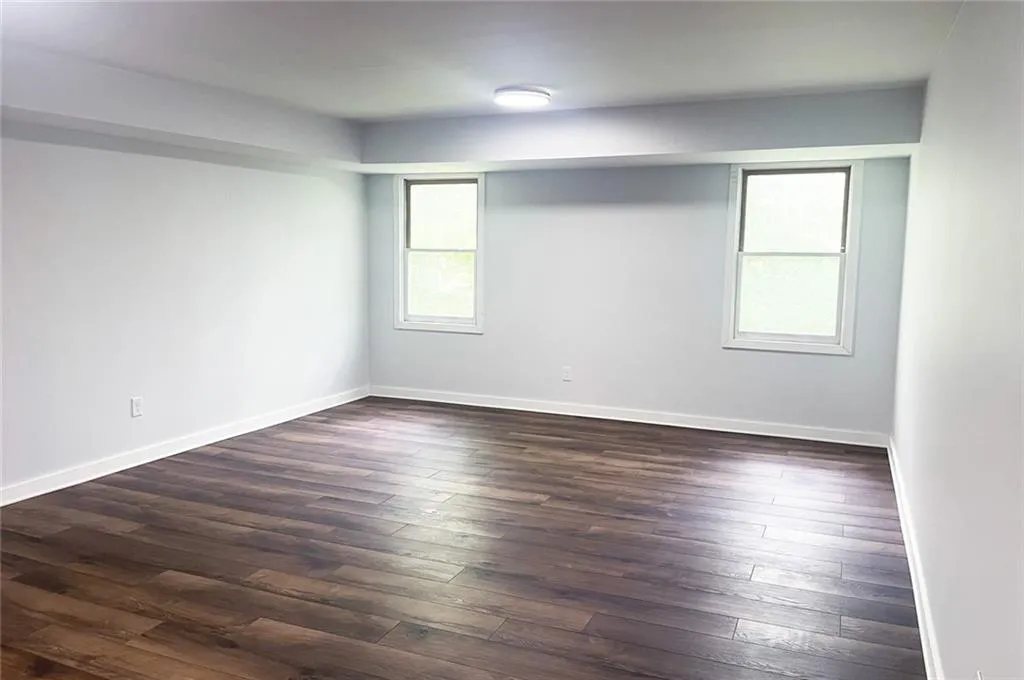 Empty room with dark wood finished floors and baseboards