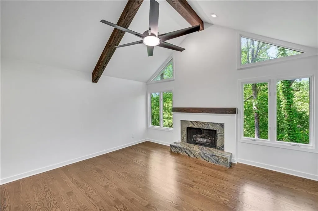 apremium fireplace, high vaulted ceiling, beamed ceiling, wood finished floors, and ceiling fan