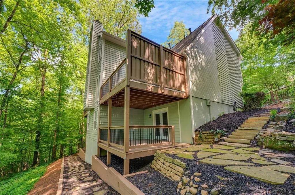 Back of property with a wooden deck, a chimney, and french doors