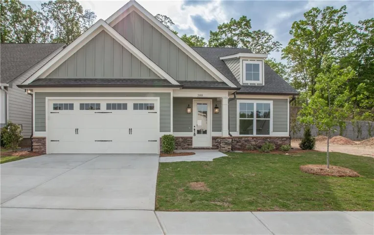 Craftsman-style home with stone siding, roof with shingles, a porch, driveway, and a garage