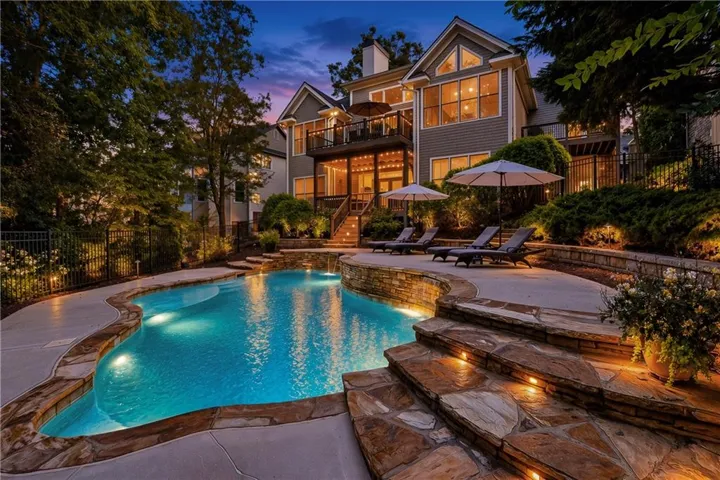 Custom-shaped swimming pool with integrated lighting, a stone-clad retaining wall, and natural stone steps