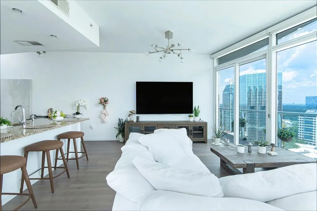 Living room featuring light wood-type flooring, floor to ceiling windows, and a chandelier