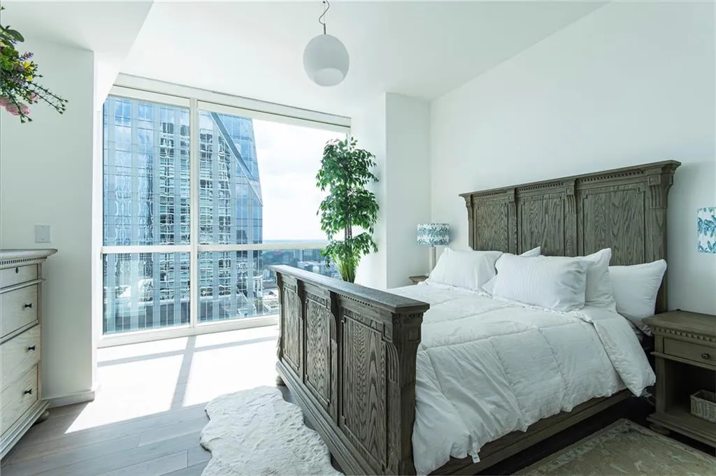Bedroom with expansive windows, wood finished floors, and a view of city