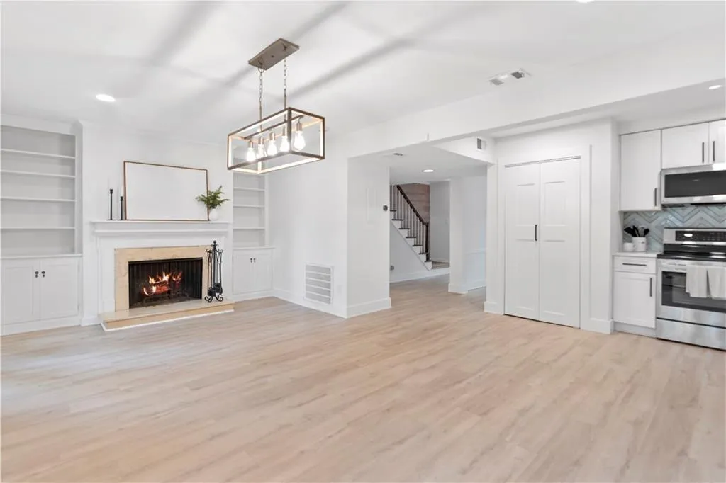 Unfurnished living room with stairs, light wood-style floors, a premium fireplace, built in features, and recessed lighting