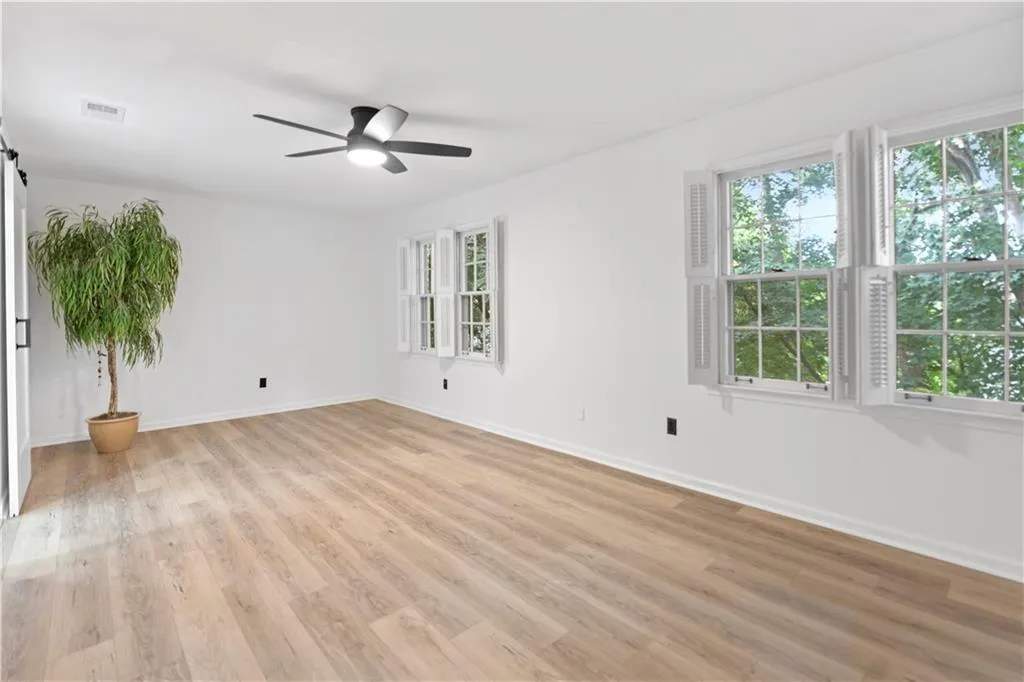 Spare room with a ceiling fan, light wood-style flooring, and a barn door
