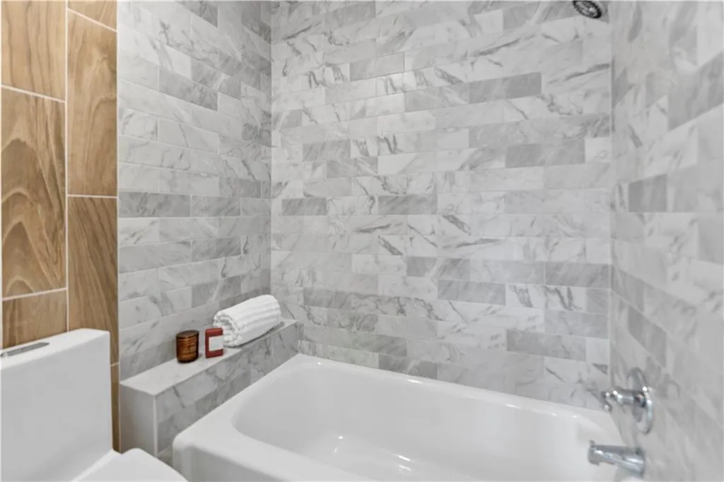 Ensuite bathroom featuring bathing tub / shower combination and toilet