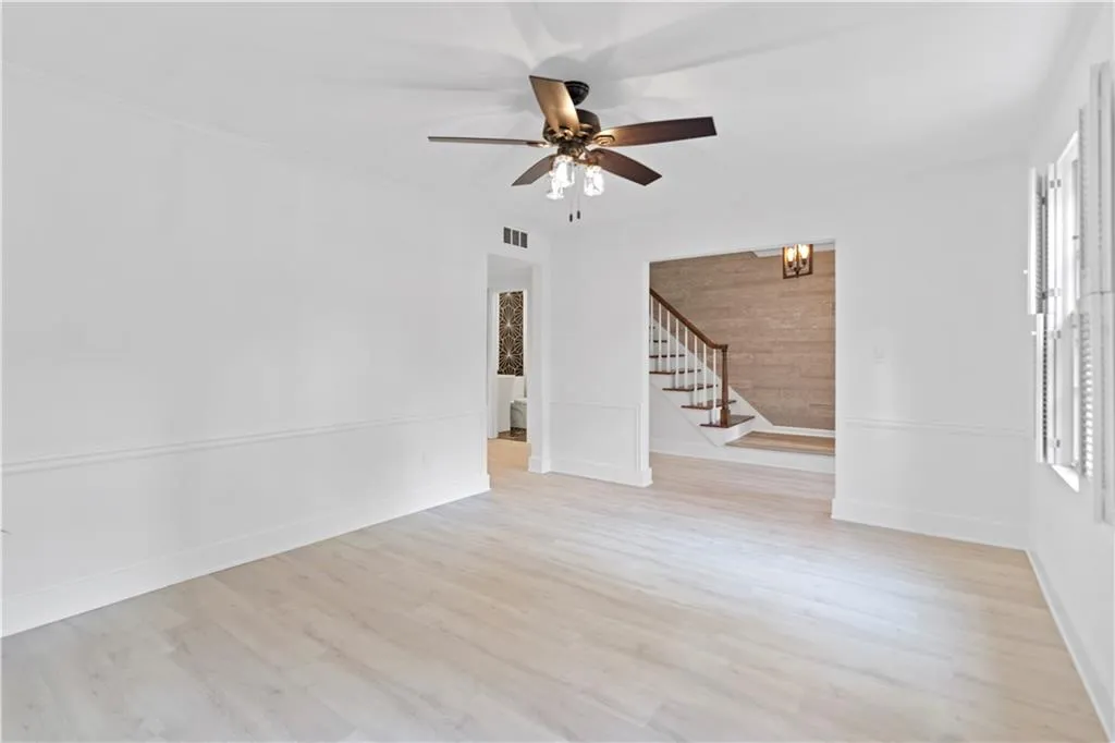 Unfurnished room featuring stairs, ceiling fan, and wood finished floors