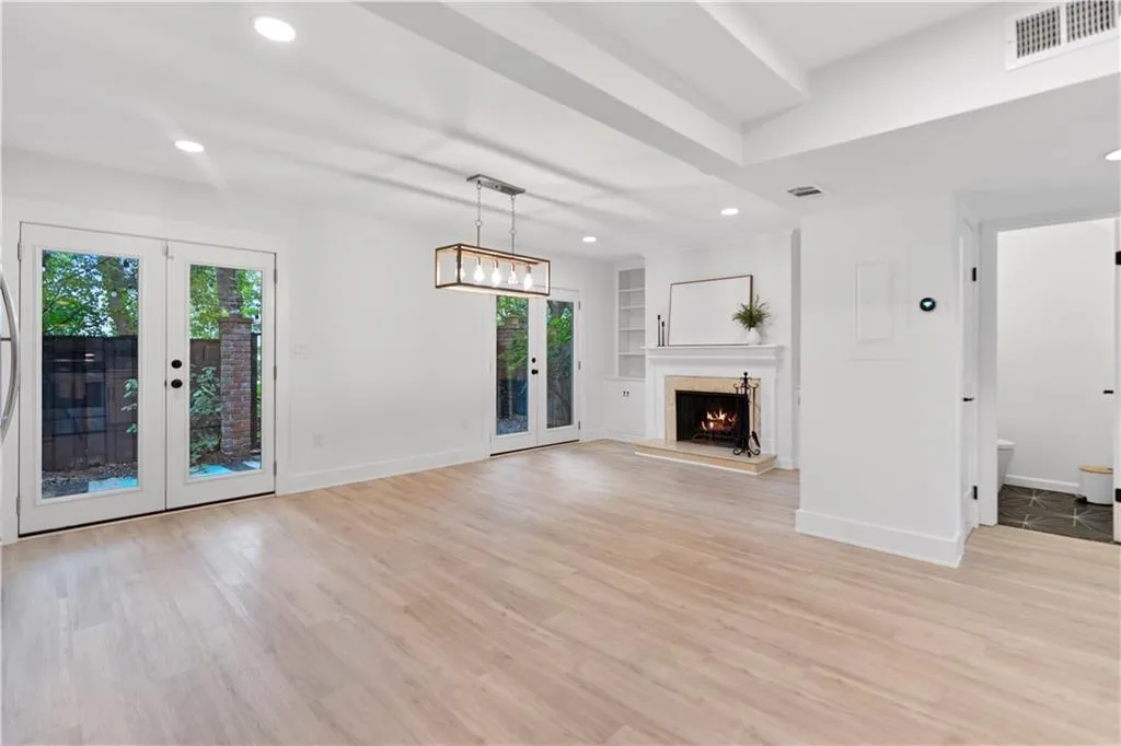 Unfurnished living room with french doors, recessed lighting, light wood-style floors, a fireplace, and built in shelves