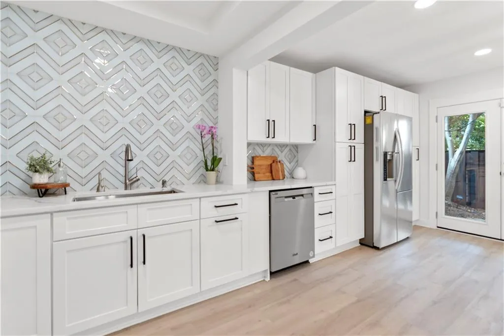 Kitchen featuring appliances with stainless steel finishes, light wood finished floors, white cabinetry, tasteful backsplash, and recessed lighting