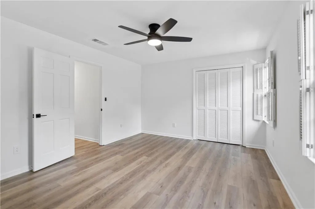 Guest bedroom featuring a closet, light wood-style flooring, and a ceiling fan
