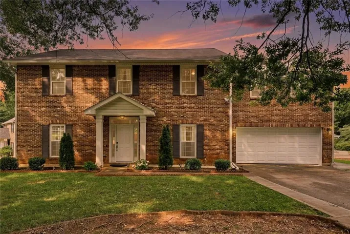 Brick exterior home featuring a covered entryway, white front door, and a two-car garage