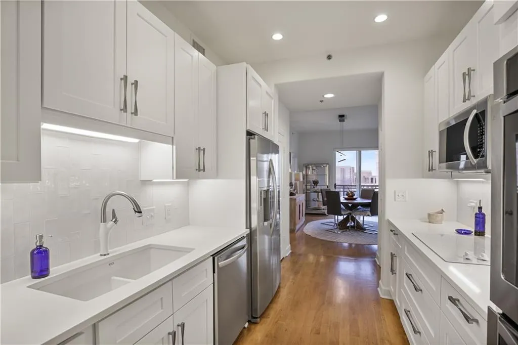 Kitchen with light hardwood / wood-style floors, white cabinets, tasteful backsplash, pendant lighting, and appliances with stainless steel finishes