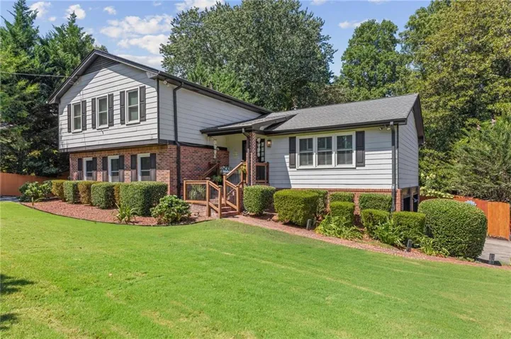 Charming brick and siding home set on a manicured lawn with mature landscaping