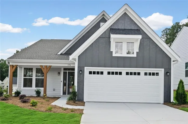 Contemporary exterior featuring a two-car garage, dark gray vertical siding, light gray horizontal siding, a covered entry with a wood-finish column, and a newly sodded lawn with fresh landscaping