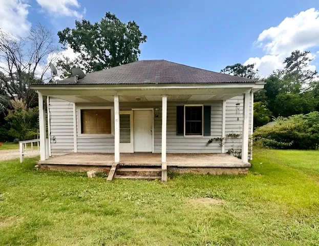 Classic cottage-style home featuring white horizontal siding, a covered front porch with substantial support columns, and a gabled roof