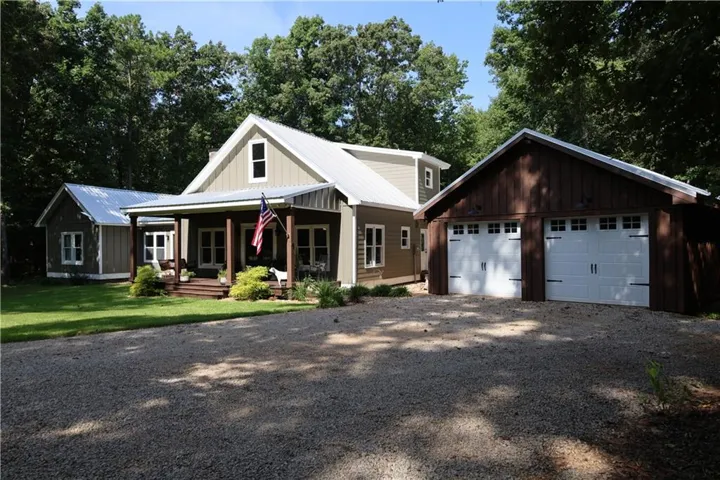 Gable-front home with a metal roof, an attached covered porch, and a gravel driveway