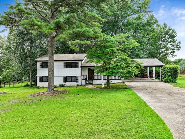 Two-story exterior with white siding, black shutters, covered front porch, and an attached carport