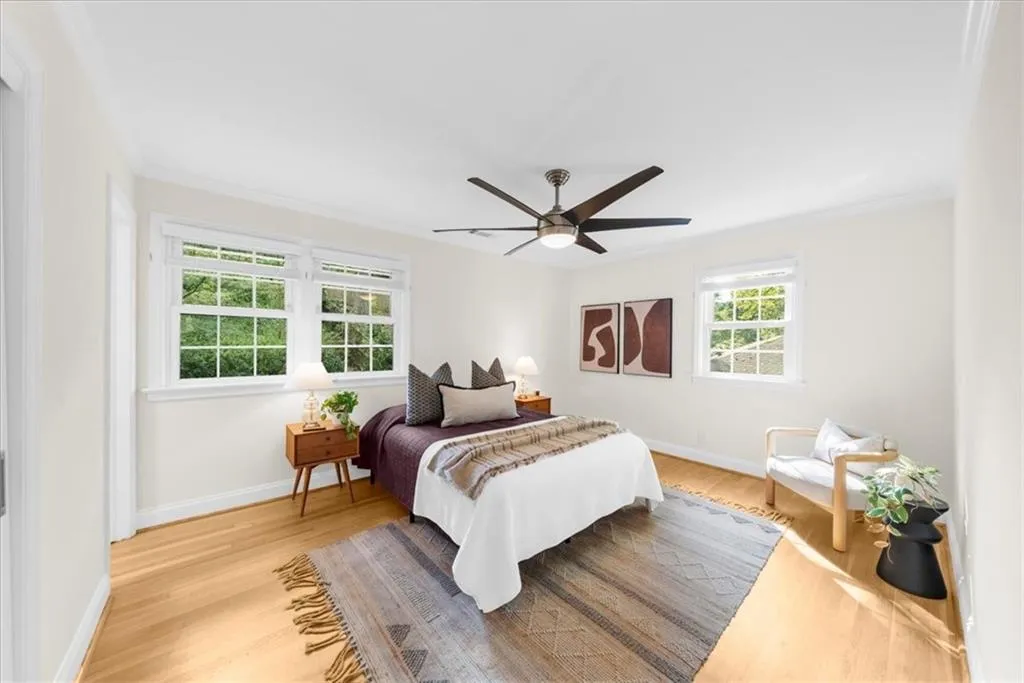 Bedroom with light wood-style flooring, crown molding, and ceiling fan