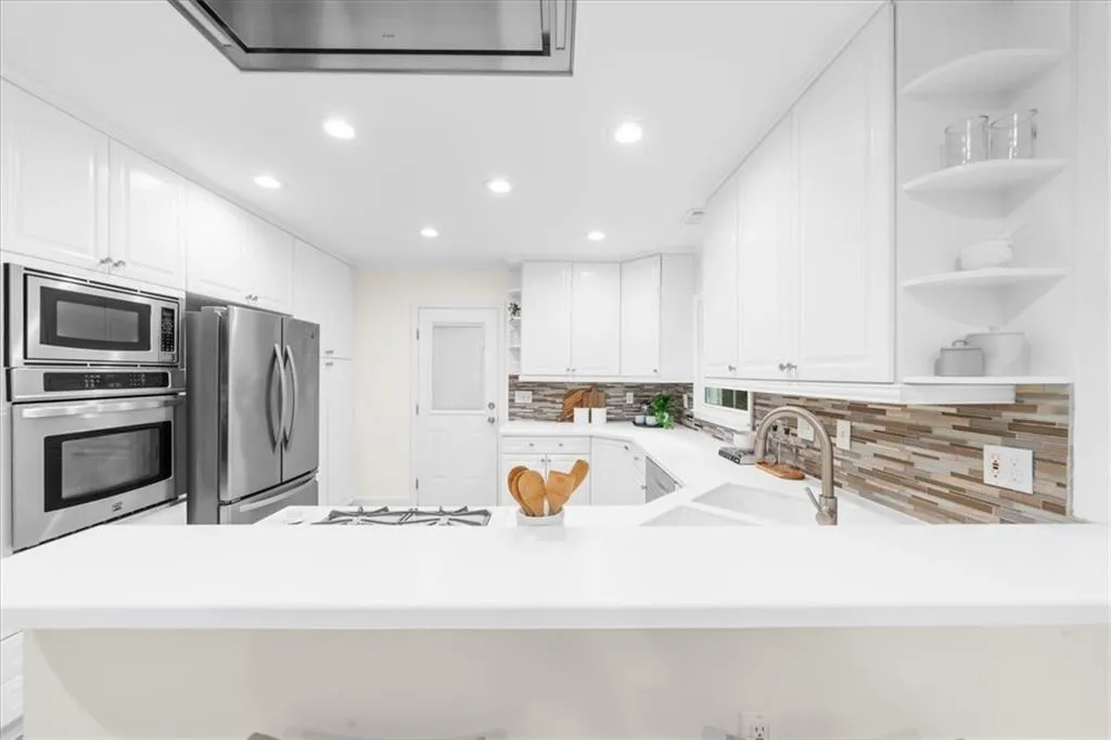 Kitchen with open shelves, stainless steel appliances, white cabinetry, recessed lighting, and a peninsula