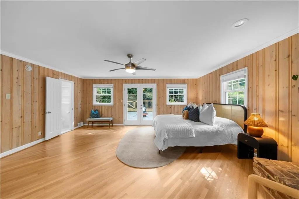 Bedroom featuring wood finished floors, access to exterior, french doors, ornamental molding, and ceiling fan