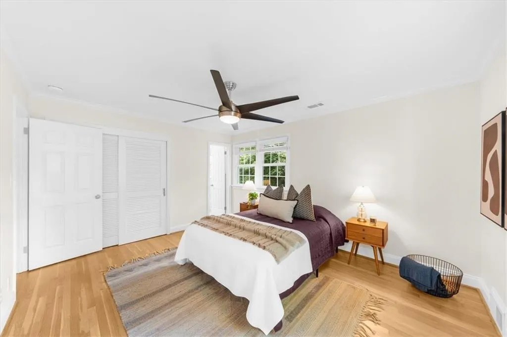 Bedroom with light wood finished floors, a closet, ceiling fan, and ornamental molding