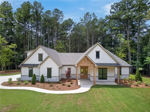 Modern farmhouse exterior with board and batten siding, stone accents, gabled rooflines, a covered front entry with wood beam details, and a concrete pathway