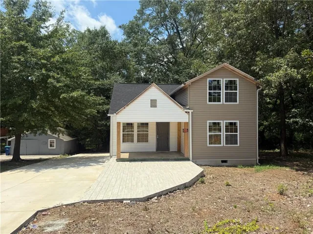 View of front of property featuring driveway, crawl space, and view of wooded area