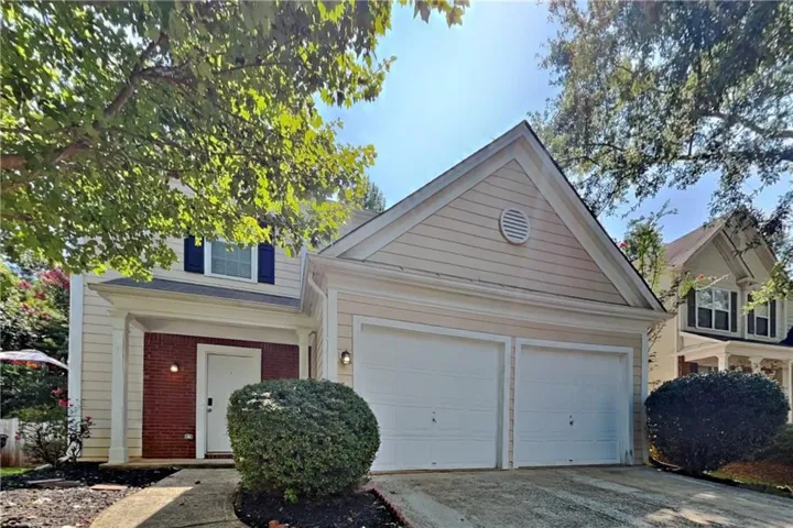 Exterior featuring a two-car garage, brick facade accents, and a covered entry