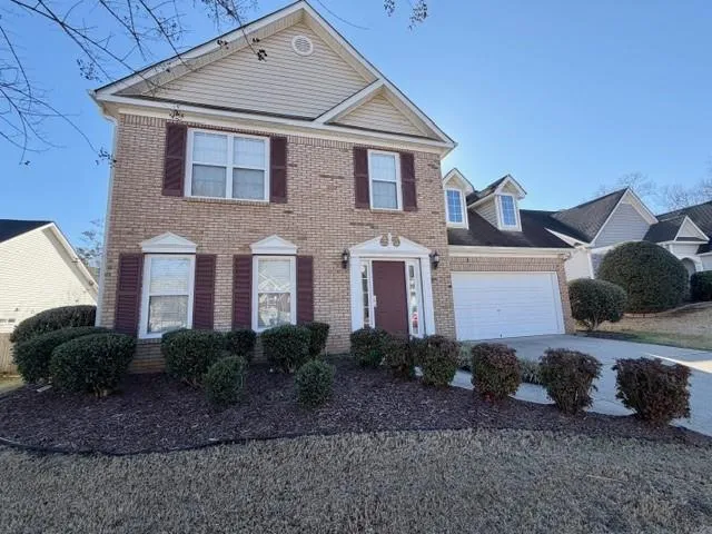 Colonial-style house featuring driveway, brick siding, and an attached garage