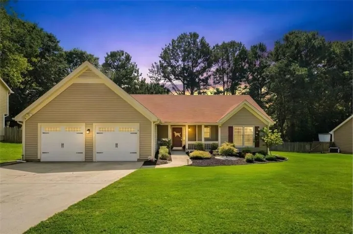 Siding exterior with a gable roof, covered front porch, attached two-car garage, and landscaped front yard with a concrete driveway