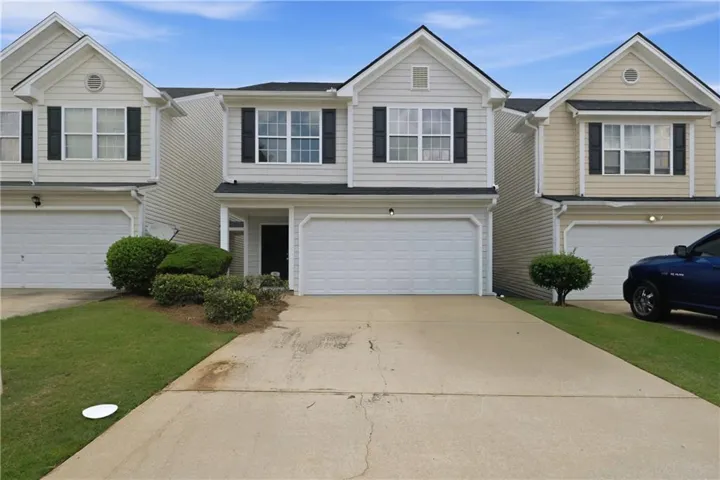 Two-story townhome with light-colored siding and a black front door