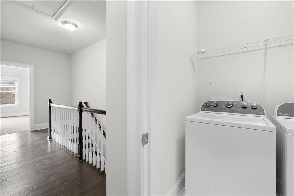 Laundry room with wood finished floors, attic access, and washer and clothes dryer