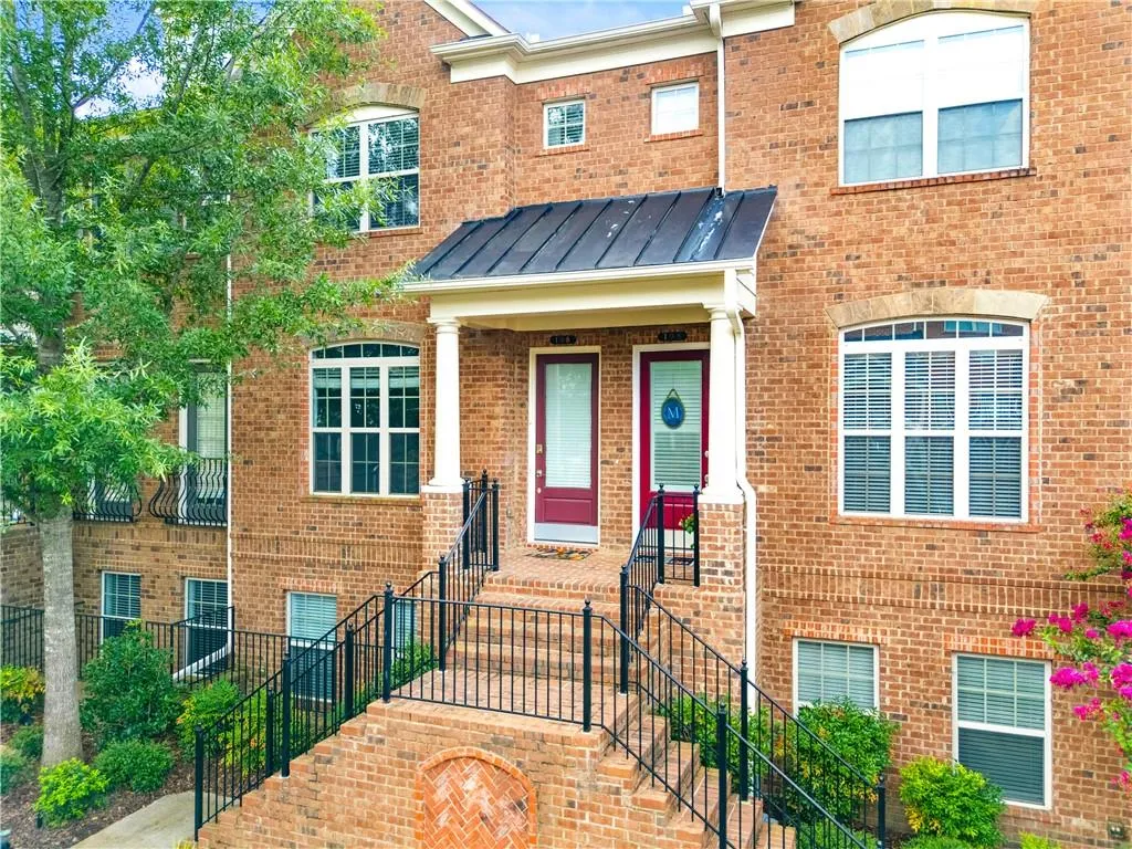 View of front of house with a standing seam roof, a metal roof, brick siding, and stairs