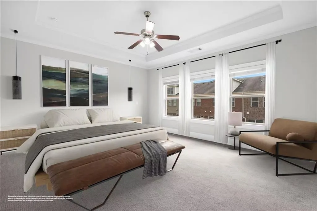 Bedroom featuring a raised ceiling, multiple windows, carpet flooring, a ceiling fan, and ornamental molding