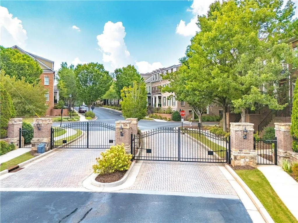 View of asphalt street with a gate, curbs, sidewalks, and a gated entry