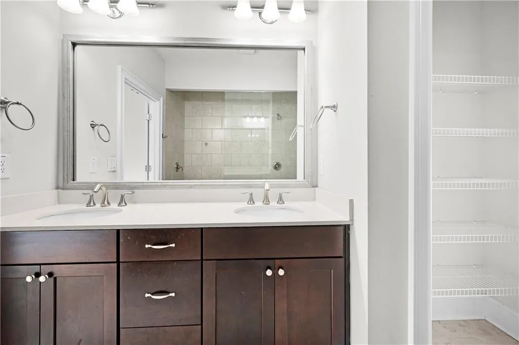Full bath featuring double vanity, a tile shower, and light tile patterned floors