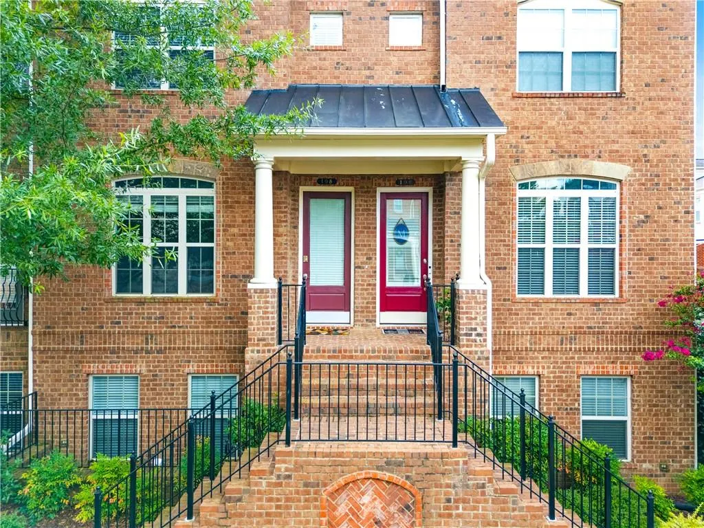 Doorway to property with a standing seam roof, a metal roof, brick siding, and a porch